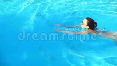 阳光明媚的夏日，身着比基尼和太阳镜的年轻黑发女子在游泳池游泳